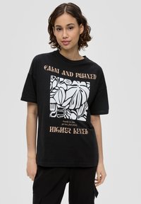 Schwarzes Baumwoll-T-Shirt mit einem weißen abstrakten Blättergrafik und Text. Kurze Ärmel, lockere Passform und runder Ausschnitt.