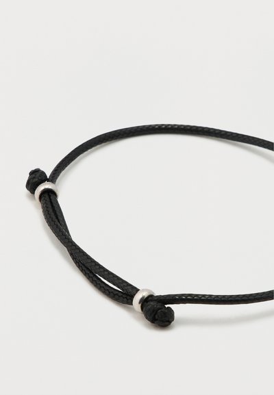 Mustast punutud nöörist käevõru, millel on hõbedane metallhelmeste aksessuaar ja sõlmitud detailid, luues reguleeritava kujunduse.