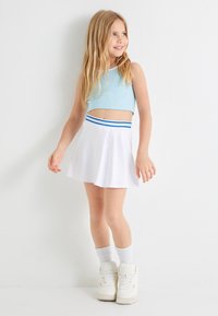 Lys blå cropped top med ribbet tekstur, parret med en hvid skørt med flared silhuet og en blå-stribet talje. Hvide høj-top sneakers.