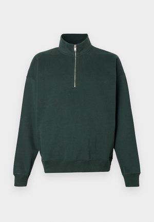 Mörkgrön sweatshirt med hög krage och dragkedja fram. Har långa ärmar och ribbade muddar vid nederkant och ärmar. Mjuk textur.
