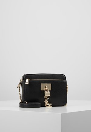 Zwarte leren crossbodytas met een gestructureerde afwerking, gouden hardware, een hangslotdetail en een afneembare kettingriem. Ritssluiting aan de bovenkant.