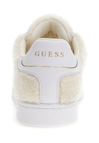 White sneaker with fluffy cream textile and white leather accents. Features a gold "GUESS" logo on the back and a textured rubber sole.