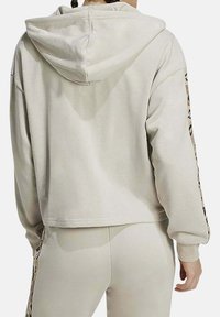 Felpa corta beige con cappuccio e maniche lunghe, con dettagli in stampa animalier lungo le maniche e tessuto morbido e testurizzato.