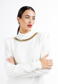 Pulover alb din tricot cu guler înalt și umeri bufanți, împodobit cu o colier din lanț aurit. Textură netedă, cu o siluetă fit.