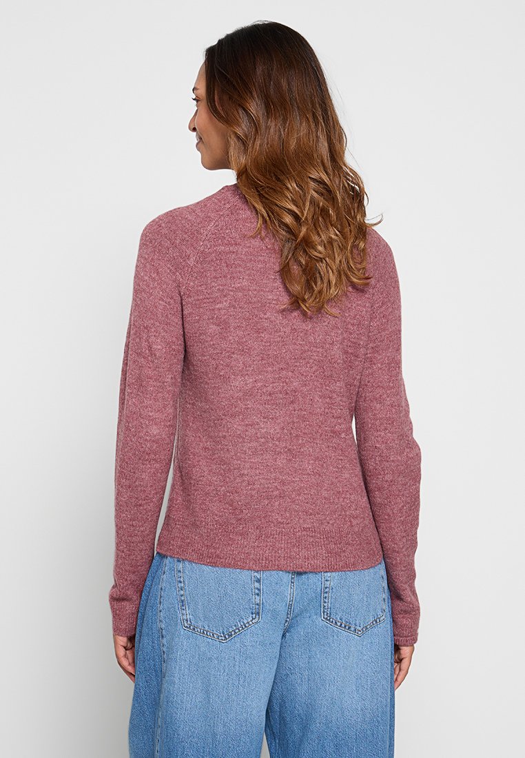 Maglione lavorato a maglia bordeaux con maniche raglan, orlo a coste e finitura testurizzata, abbinato a jeans chiari a vita alta. Design semplice e casual.