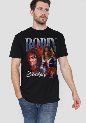 Man wearing black t-shirt with three different portraits of a woman and the text "Robin Buckley" on front.