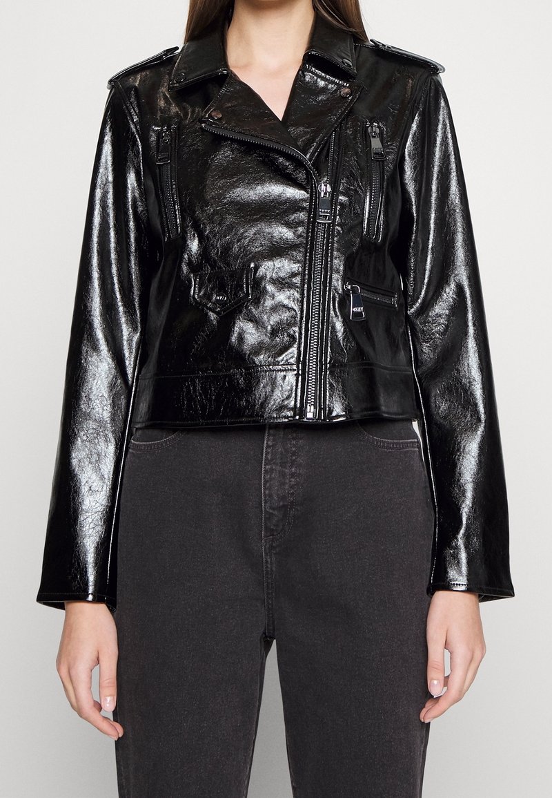 Svart läderbikerjacka med en glänsande finish, utrustad med dragkedjor, bröst- och sidofickor, samt en kortad design.