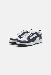 Marineblaue und weiße Sneakers aus perforiertem Leder, mit Gummisohle, Schnürsenkeln und gepolstertem Kragen. Ausgestattet mit einem Logo auf der Zunge und stilvollen Designelementen.