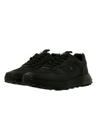 Paire de baskets noires avec tissu texturé et semelles épaisses en caoutchouc, vues d’un angle frontal bas sur fond blanc.