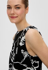 Schwarzes ärmelloses Kleid mit einem weißen Blumenmuster, Rundhalsausschnitt und lockerem Schnitt, aus einem leichten Stoff gefertigt.