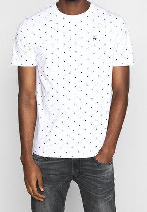 Witte T-shirt met korte mouwen en een zwart stippenpatroon. Heeft een ronde halslijn en een klein logo op de borst.