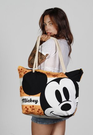 Bolsa de mano de lona con una gran cara de Mickey Mouse en blanco y negro, con acentos en naranja y blanco y asas de cuerda natural.
