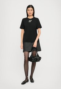 Μαύρο μπλουζάκι με κοντά μανίκια και σχέδιο "BF", γκρι τζιν φούστα, μαύρες καλσόν με σχέδια, φλατ μαύρα παπούτσια και μια μικρή μαύρη τσάντα.