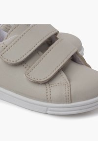 Scarpe beige con velcro, dotate di una tomaia sintetica liscia, suola in gomma bianca e dettagli di cucitura. Punta arrotondata e due cinturini regolabili.