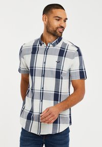 Camisa de cuadros de manga corta en azul, blanco y gris con cuello abotonado y un logo en el pecho. Tejido de mezcla de algodón.