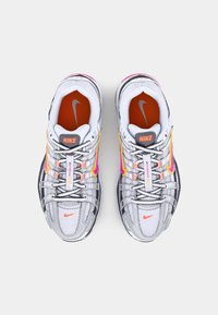 Pair of white, gray, and pink Nike sneakers with orange insoles and black-and-white laces, viewed from above on a plain background.