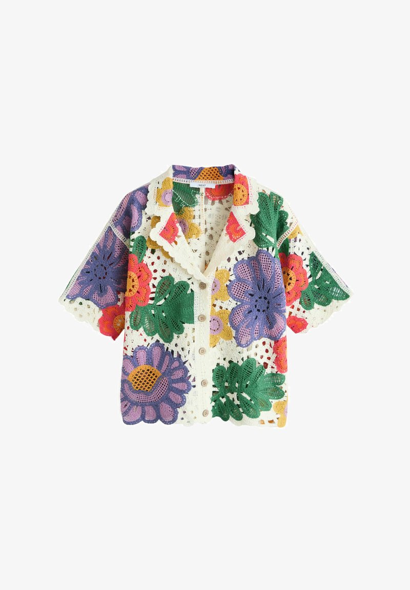 Camisa de manga corta con botones de crochet con patrones florales multicolores en tonos morado, verde, rojo, amarillo y bordes ondulados blancos.