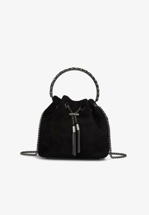 Bolso de bucket de ante negro con un mango superior redondeado y correa de cadena, con herrajes en tono plateado y borlas decorativas.