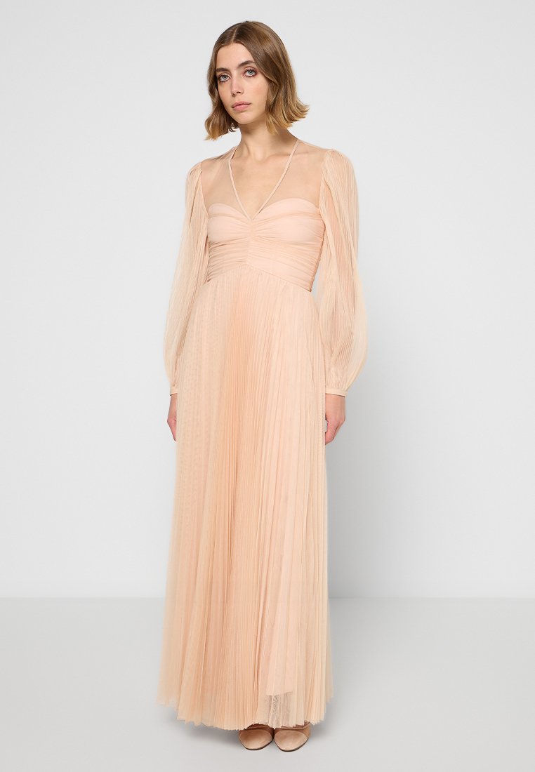 Pleated floor-length dress in soft peach fabric with sheer long sleeves and a fitted bodice, featuring delicate texture and a V-neckline.