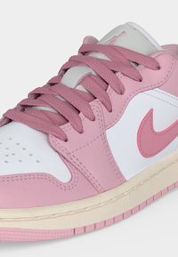 Gros plan d'une basket rose et blanche avec des lacets roses et un logo Nike Swoosh rose sur le côté.
