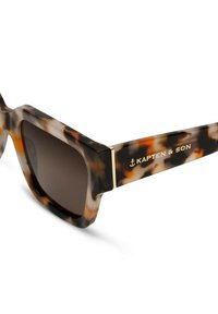Sluneční brýle s želvovinovým vzorem, širokým čtvercovým rámem, tmavými skly a zlatými akcenty. Na boku se nachází název značky "KAPTEN & SON".
