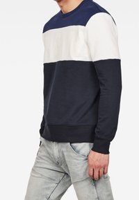Sudadera con bloques de color en azul marino, blanco y gris claro, con mangas largas, puños y dobladillo acanalados. Tejido suave de mezcla de algodón, cuello redondo.