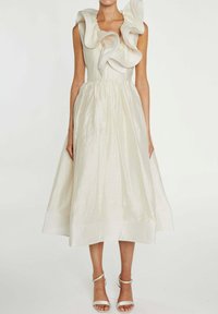 Lys beige midi kjole med tekstureret stof, har en flæsekantet halsudskæring, tætsiddende overdel og en flagrende nederdel. Båret med sølvfarvede sandaletter med remme.
