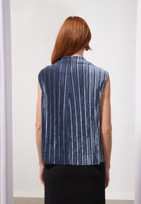 Námořnická modrá bezrukávová blůza s vertikálně pruhovanou texturou a měkkým sametovým materiálem, s vysokým výstřihem a volným střihem.