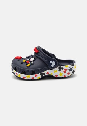 Navy blue plastic clogs with decorative Mickey Mouse appliqué, featuring a white sole adorned with colorful stars and Mickey silhouettes.