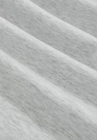 Svetlo šedá látka s jemnou textúrou, s mäkkými záhybmi a mierne melírovaným vzhľadom, prezentujúca hladký a ľahký dizajn.