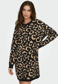 Robe en maille noire avec un imprimé léopard beige, coupe oversize, manches longues, poignets côtelés et encolure ronde. Texture lisse.