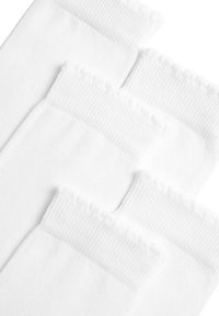 Calzini bianchi in cotone con texture a coste, caratterizzati da un bordo frill e un corpo liscio. Quattro calzini individuali disposti piatti.