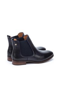 Bottines Chelsea en cuir noir avec des panneaux élastiques sur les côtés, bouts ronds et talons en bois, présentant une texture lisse et des détails de couture subtils.