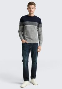 Herrenlangarmpullover in Navy und Grau mit einem strukturierten Design. Kombiniert mit dunklen Jeans und weißen Sneakern. Einfacher, lässiger Look.