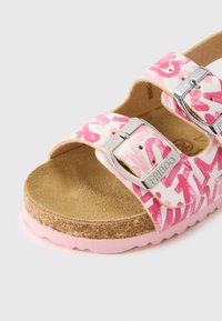 Rózsaszín mintás szandálok két állítható ezüst csattal, parafa talppal és hullámszerű szélű, texturált rózsaszín talppal.