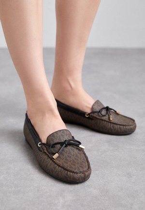 Bruine loafers met patroon, gemaakt van een getextureerd materiaal, met een zwarte veteraccent en goudkleurige hardware aan elke kant.