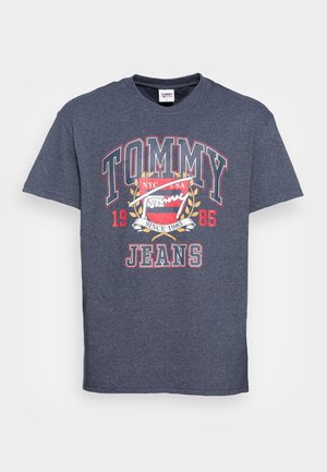 Dunkelblaues Tommy Jeans T-Shirt mit rotem, weißem und goldenen Logotext sowie einem Emblem, das "NYC USA" und "Seit 1985" auf der Vorderseite angibt.