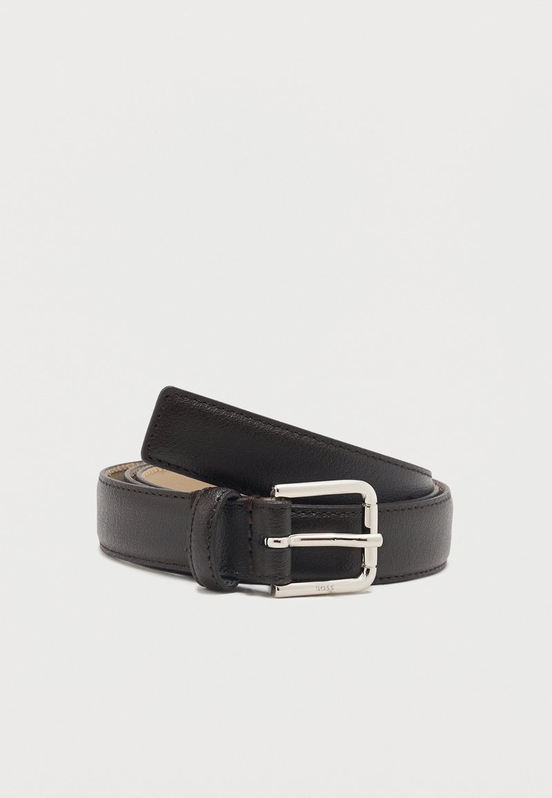 Ceinture en cuir noir roulée avec une boucle rectangulaire argentée sur un fond blanc uni.