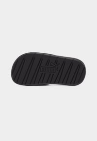 Μονάδα σόλας μαύρης παντόφλας Puma slide με διαγώνιες αυλακώσεις και λογότυπο Puma ανάγλυφο στο κέντρο, εμφανίζεται σε απλό φόντο.