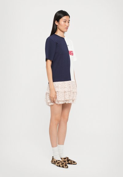 Korte mouwen jurk met marineblauw en wit kleurblokontwerp, gestructureerde roze kant rok en luipaardprint pantoffels.