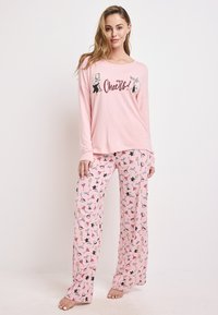 Ljust rosa långärmad pyjamaströja med "Cheers!"-grafik, ihopparad med mönstrade rosa pyjamabyxor som har drycker och festfigurer.