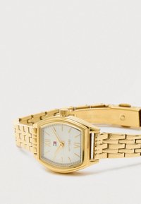 Gold-toned wristwatch with a linked metal band, a white face, Roman numerals at 6 and 12, and a small rectangular logo near the center.
