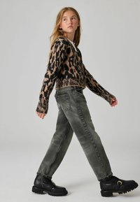 Suéter de estampado de leopardo en tonos beige y negro, combinado con jeans grises de tiro alto y botas negras hasta el tobillo con suelas gruesas.