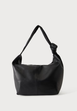 Sac à bandoulière en cuir noir avec une sangle nouée unique et un corps souple et décontracté de forme rectangulaire.