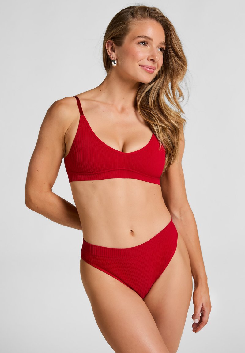 Rode geribbelde bikinibovenkant met dunne bandjes en een diepe V-hals, gecombineerd met bijpassende hooggezette bikinitaille. Glad textuur over het geheel.