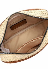 Bolso de cuero marrón con un exterior de paja trenzada. El cierre de cremallera revela un forro de tela beige con un bolsillo interno y una etiqueta.