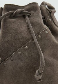 Bottes chelsea en suède marron avec une forme arrondie, des clous en métal décoratifs et un lien de fermeture avec une finition texturée.