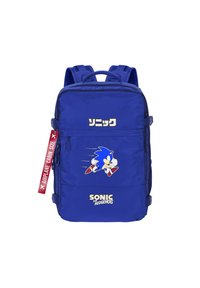 Mochila de nailon azul con un gran gráfico de Sonic the Hedgehog, bolsillo frontal con cremallera y etiqueta "TAMAÑO CABINA DE AVIÓN" en rojo.