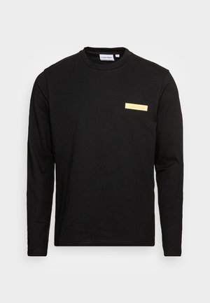 Schwarzes Langarm-T-Shirt aus Baumwolle mit Rundhalsausschnitt. Es verfügt über ein kleines, rechteckiges gelbes Logo im Brustbereich.