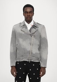 Jachetă de motocicletă din denim gri, cu modele ușoare asemănătoare norilor, închidere cu fermoar, guler larg și talie cu curea. Asortată cu pantaloni negri cu cuie metalice.